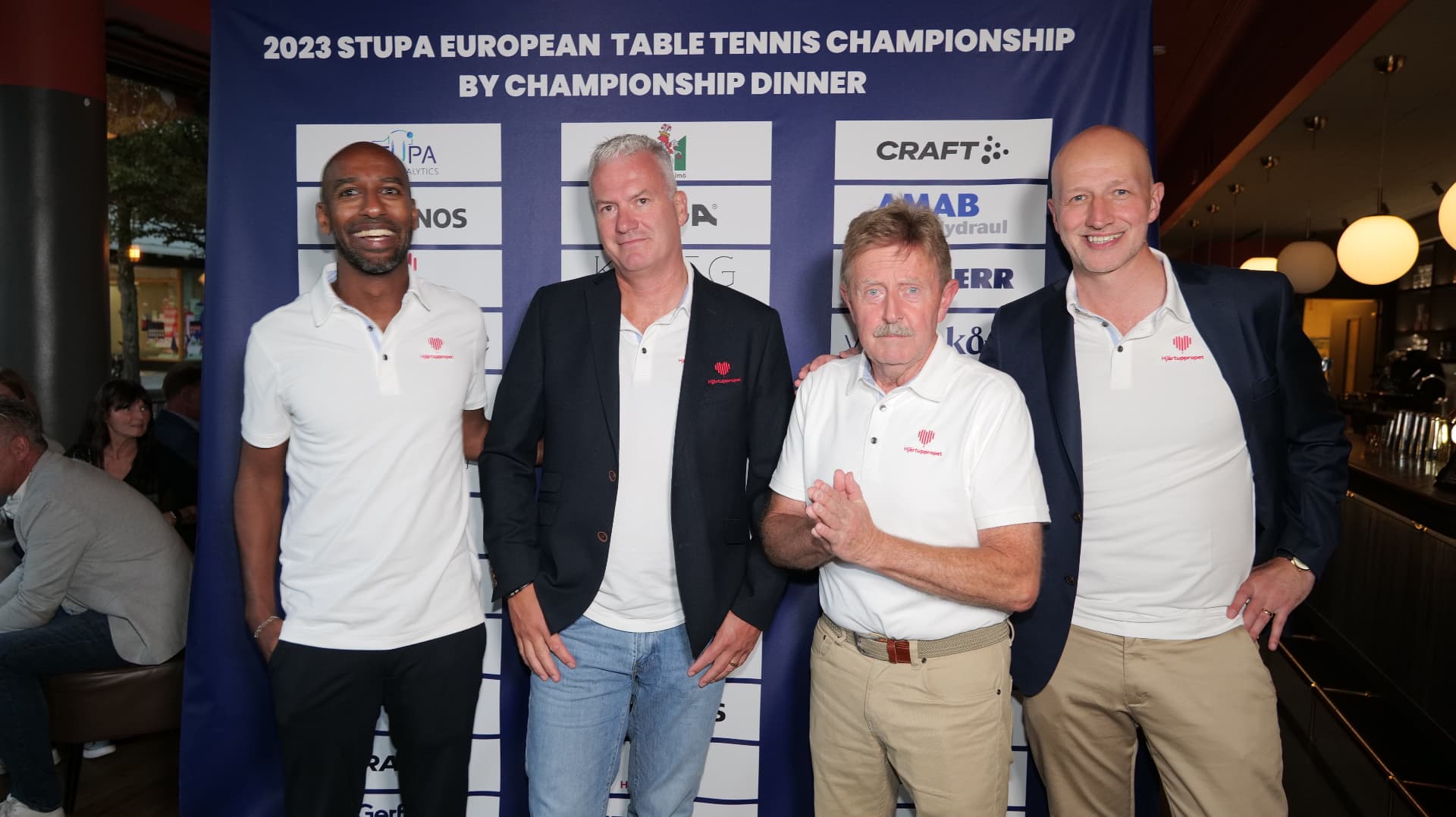 Guests in Hjärtuppropet shirts in front of the dinner backdrop at the Championship Dinner during the World Champions' Dinner in Malmö