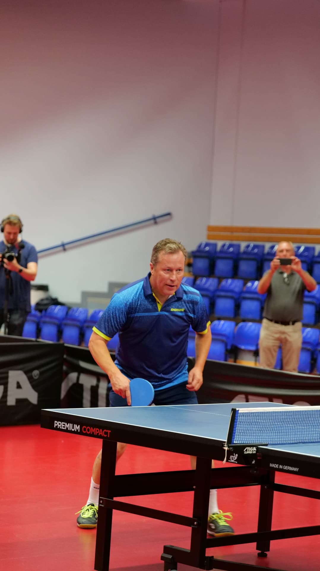 Player in a blue shirt mid-stroke during the exhibition table tennis match at the World Champions' Dinner in Malmö