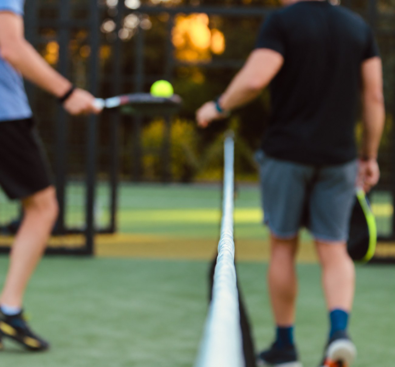 Padel player at the net in evening light